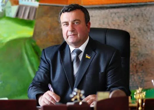 Міський голова Дубна в костюмі сидить за столом у кабінеті